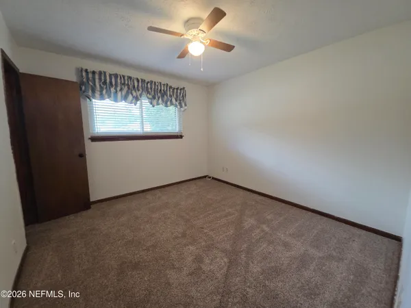 an empty room with a window and a ceiling fan