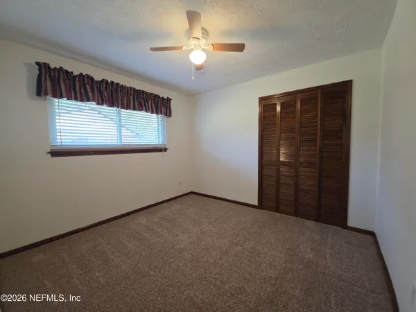 an empty room with windows and fan