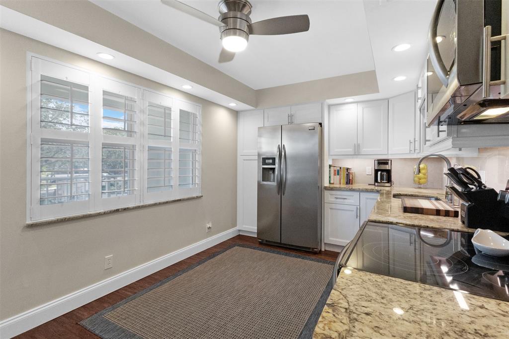 3095 North Course Drive, Unit 203 Pompano Beach, FL 33069 - Photo 15 of 49 a kitchen with stainless steel appliances granite countertop a refrigerator a sink a stove and a wooden floors