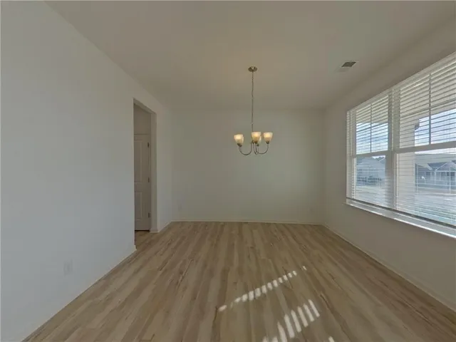 an empty room with chandelier fan and windows