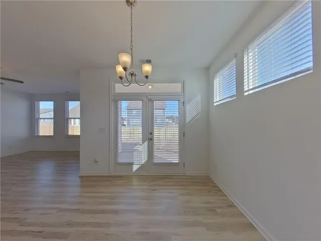 a view of a room with wooden floor chandelier and windows