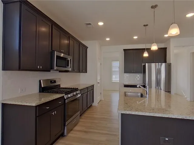 a kitchen with stainless steel appliances granite countertop a sink a stove counter space and cabinets