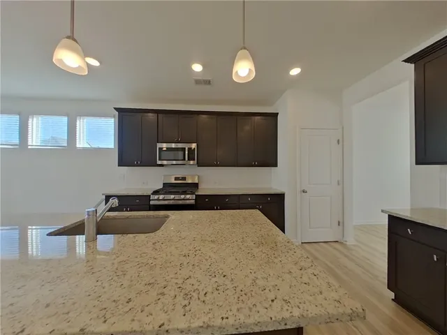 a kitchen with stainless steel appliances granite countertop a stove a sink and a microwave