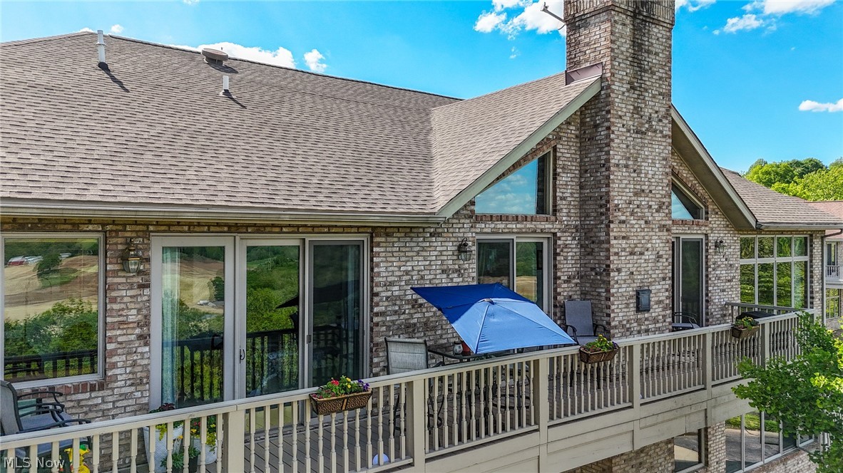 1602 Glendale Road, Unit 3 Marietta, OH 45750 - Photo 43 of 49 Exterior brick facade featuring a spacious deck with wood railing, large sliding glass doors, multiple window configurations, and a prominent brick chimney