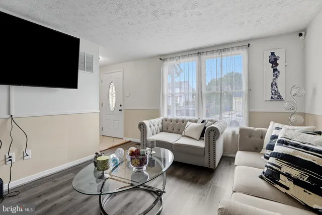 a living room with furniture a flat screen tv and a wall painting