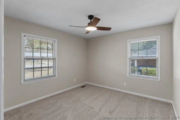 an empty room with a window and ceiling fan