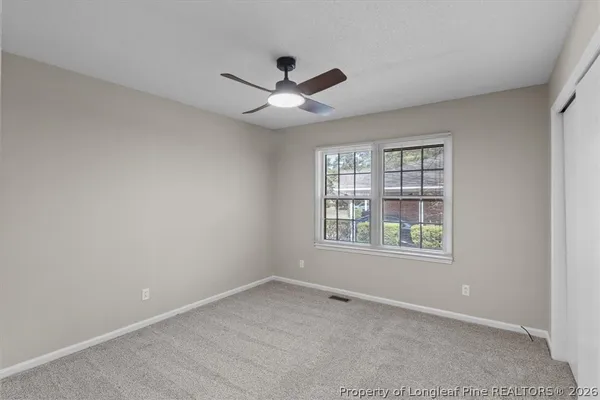 an empty room with a window and a fan