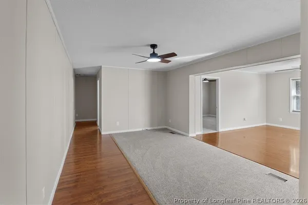 a view of a big room with wooden floor and a chandelier fan