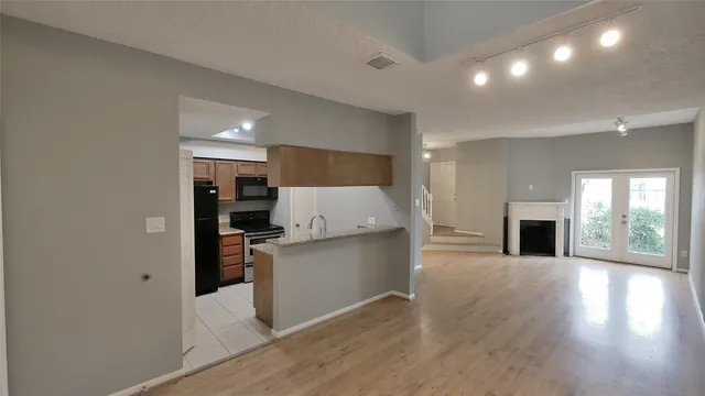 a living room with stainless steel appliances kitchen island granite countertop a refrigerator and a stove top oven