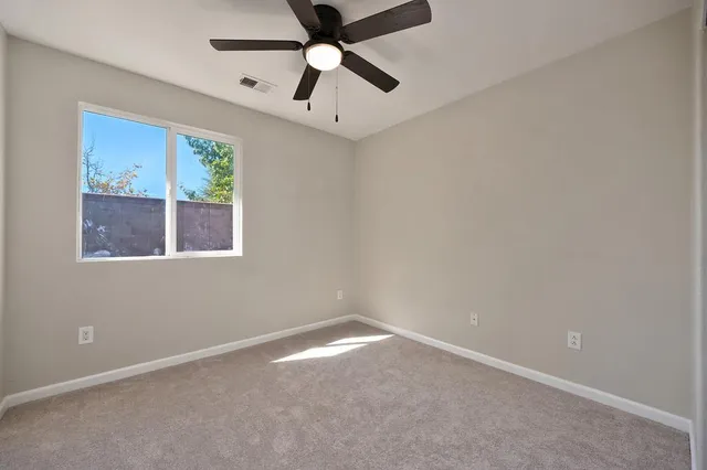an empty room with a window and a fan