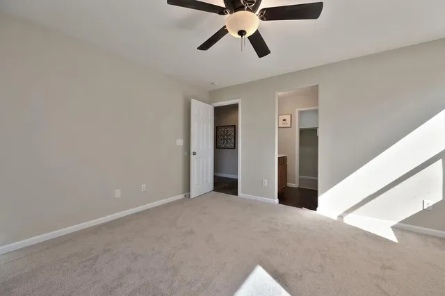 a view of an empty room and chandelier fan