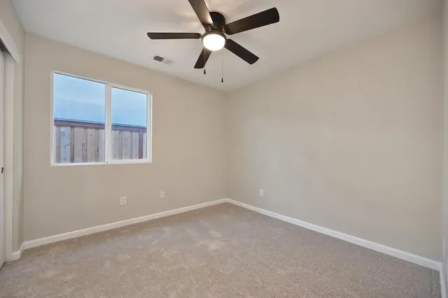 an empty room with a window and a ceiling fan