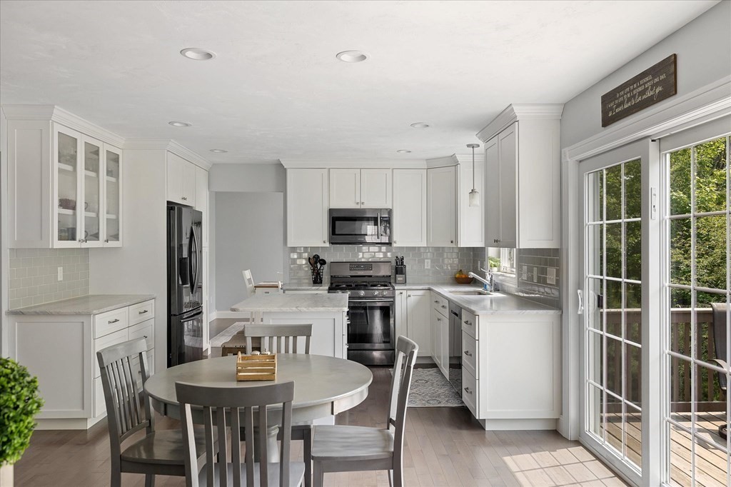15 Tannery Road Sturbridge, MA 01518 - Photo 4 of 41 a kitchen with stainless steel appliances granite countertop a stove a refrigerator a sink dishwasher a dining table and chairs with wooden floor