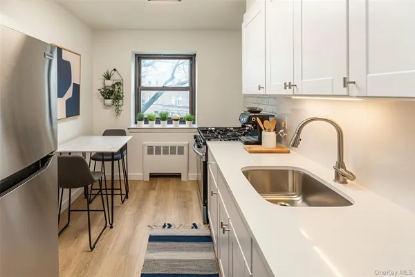a kitchen with a sink a stove and white cabinets