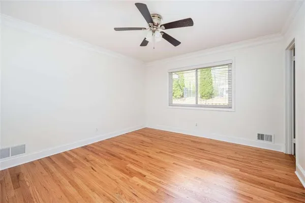an empty room with wooden floor fan and windows
