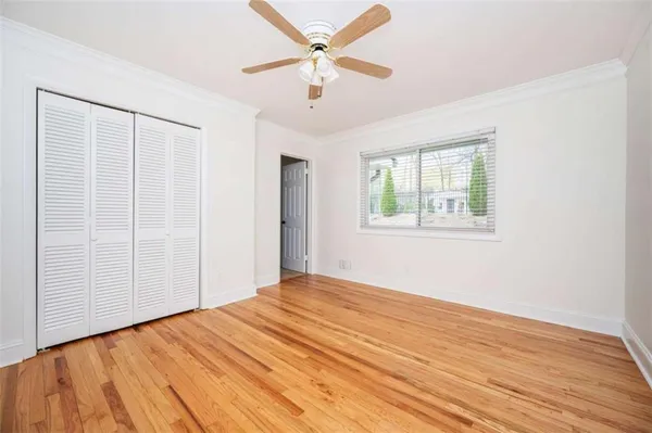 a view of empty room with wooden floor and fan