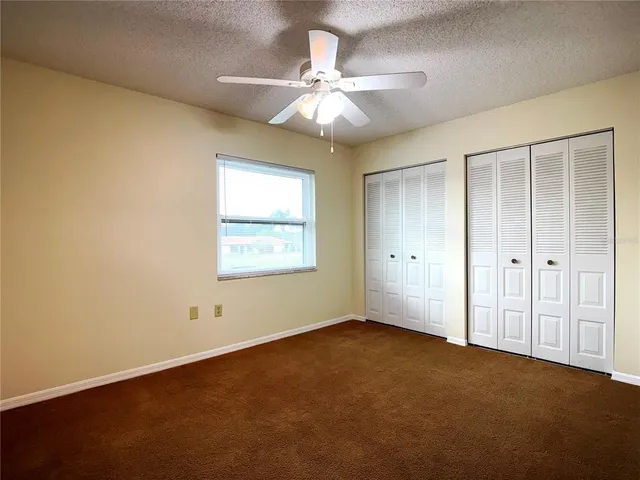 an empty room with a chandelier fan and windows