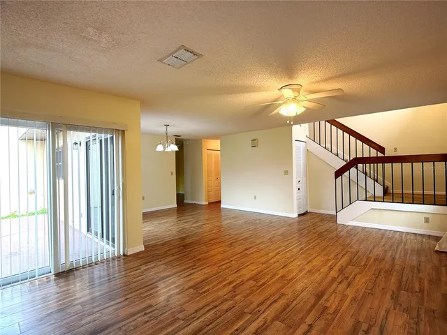 a view of empty room with wooden floor and fan