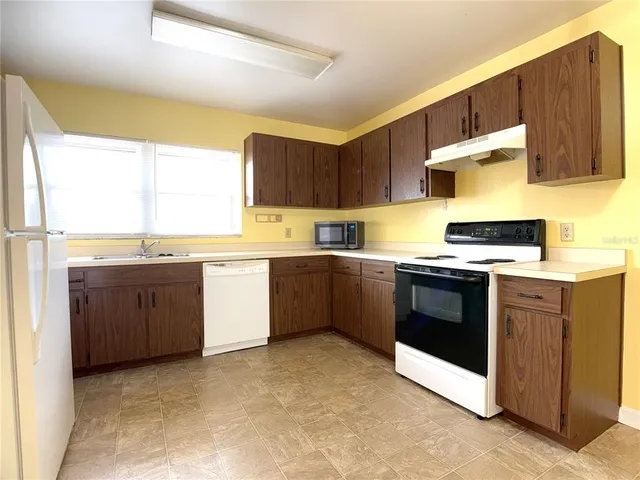 a kitchen with stainless steel appliances a stove a sink a microwave a sink and cabinets