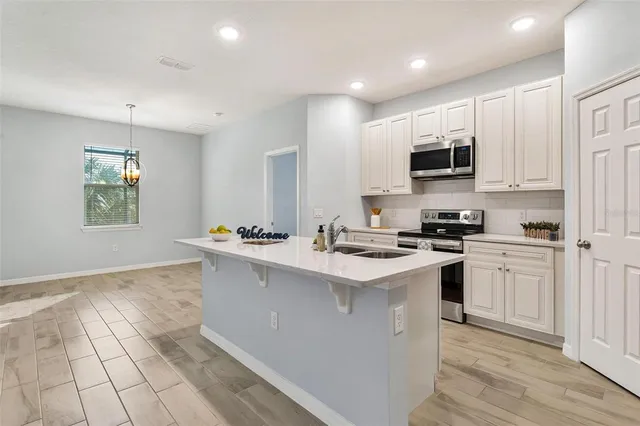 a kitchen with stainless steel appliances a sink dishwasher a refrigerator and a stove with wooden floor