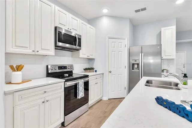 a kitchen with stainless steel appliances granite countertop a sink a stove a refrigerator and a microwave