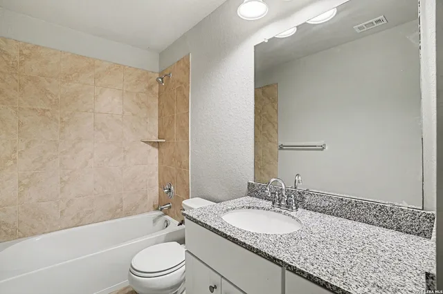 a bathroom with a granite countertop sink toilet and shower