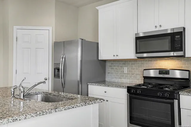 a kitchen with stainless steel appliances granite countertop a stove microwave and sink