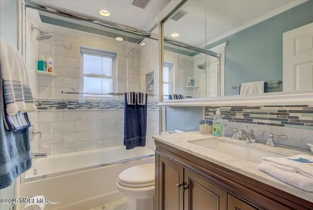 a bathroom with a granite countertop sink a toilet a mirror and bathtub