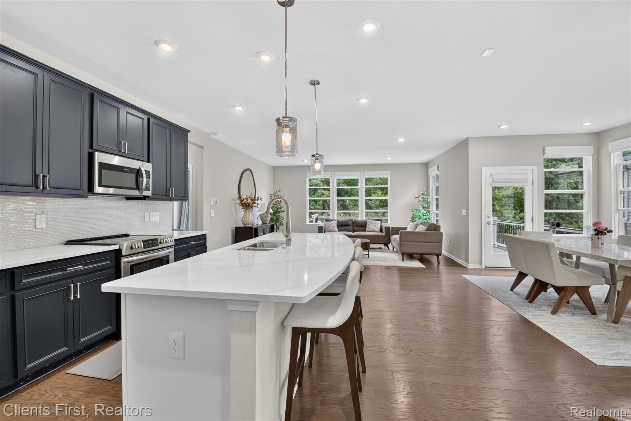4699 Bingham Road Canton, MI 48188 - Photo 6 of 47 Open-concept living space featuring a kitchen island with seating, dark blue cabinetry, stainless steel appliances, white countertops, and wood-finish flooring