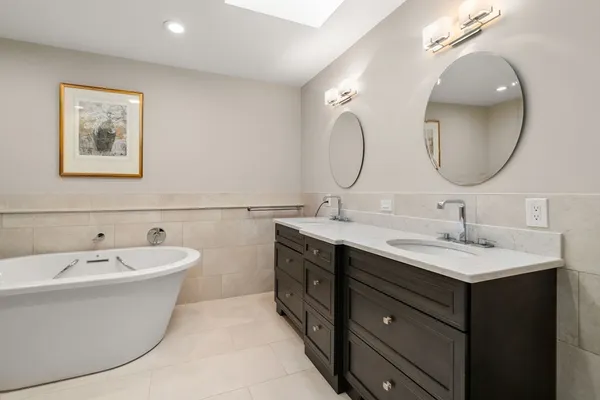 a bathroom with a double vanity sink mirror and bathtub