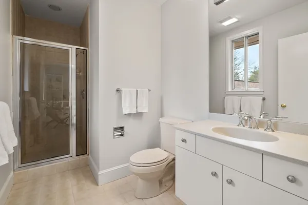 a bathroom with a toilet a sink a mirror and a shower