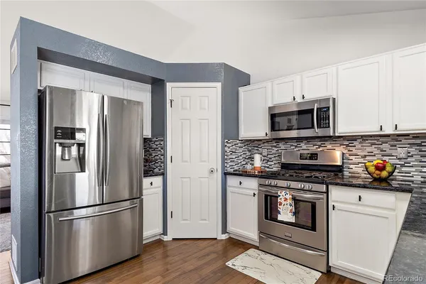a kitchen with granite countertop white cabinets and stainless steel appliances
