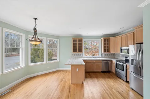 a kitchen with granite countertop a stove a sink dishwasher a refrigerator and wooden floor