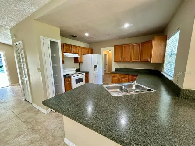 a kitchen with stainless steel appliances granite countertop a sink refrigerator and cabinets