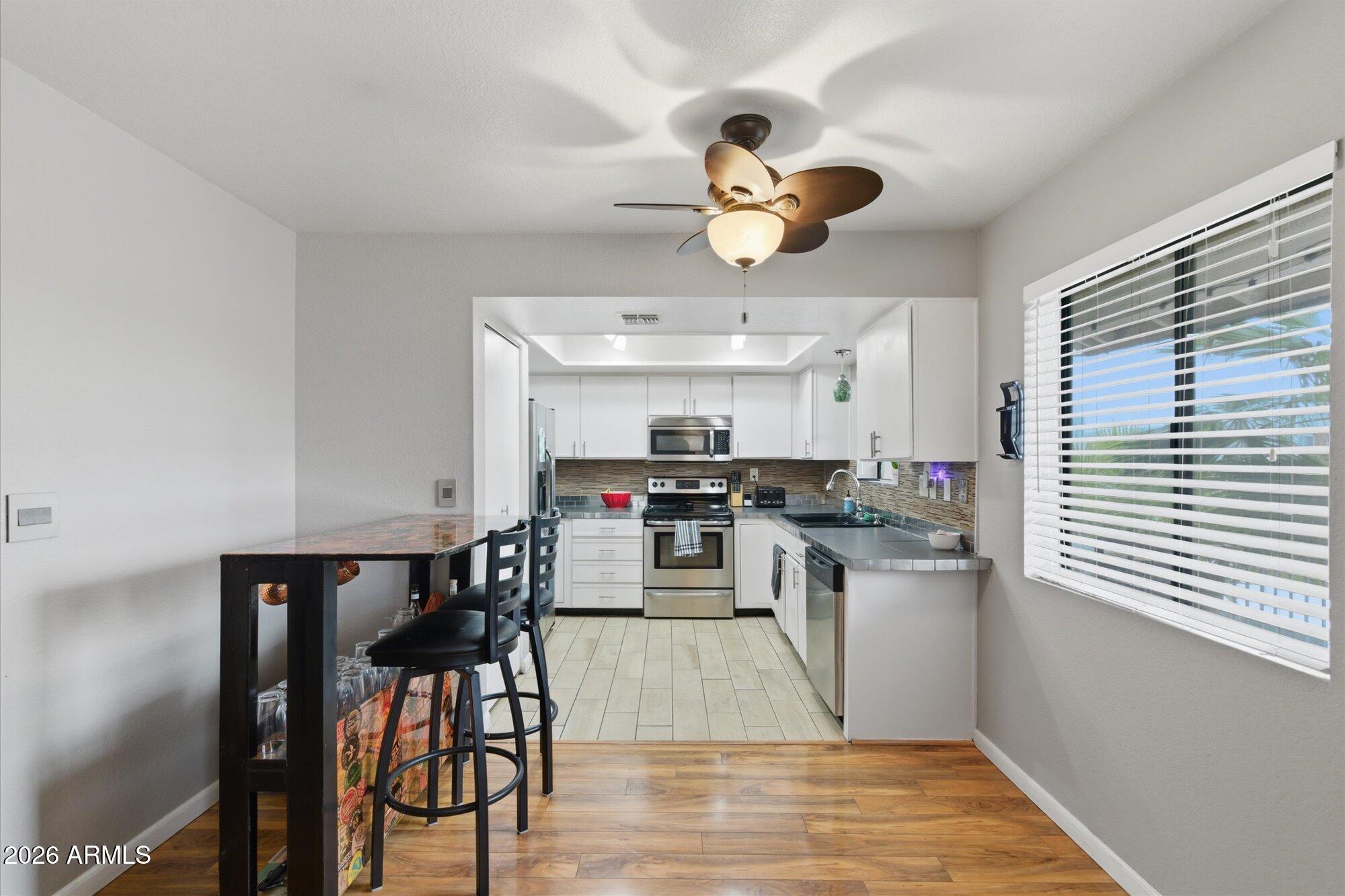 3635 North 37th Street, Unit 10 Phoenix, AZ 85018 - Photo 6 of 26 a kitchen with stainless steel appliances granite countertop a stove top oven a sink dishwasher and a dining table with wooden floor