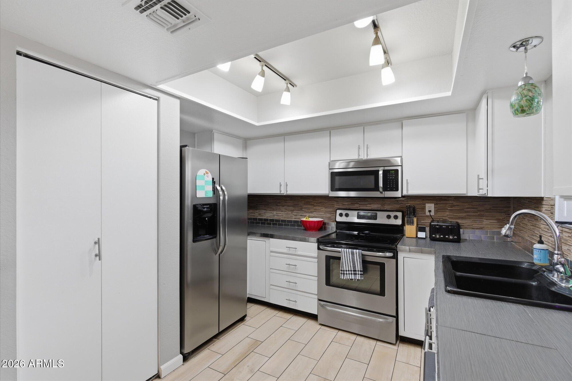 3635 North 37th Street, Unit 10 Phoenix, AZ 85018 - Photo 10 of 26 a kitchen with stainless steel appliances granite countertop a refrigerator a stove a sink and a microwave