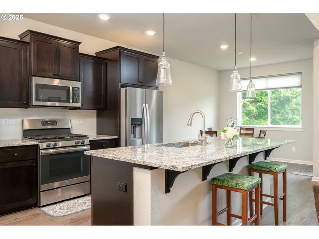 a kitchen with stainless steel appliances kitchen island granite countertop a stove refrigerator and microwave