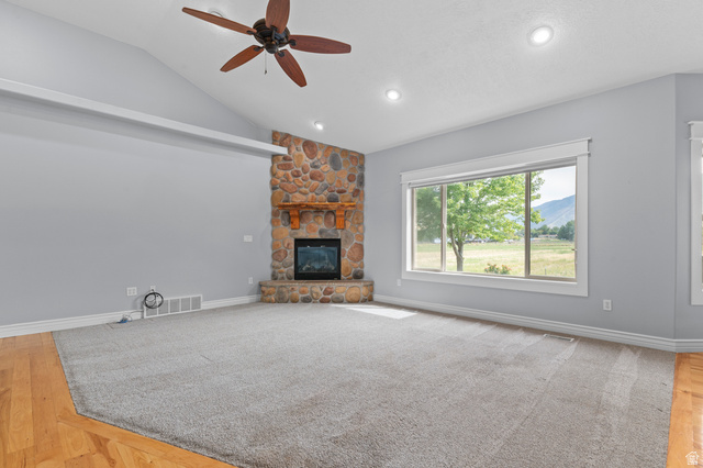 1501 West Elk Circle Mapleton, UT 84664 - Photo 15 of 39 Spacious living area featuring a stone-clad fireplace with wood mantel, vaulted ceilings, and a ceiling fan