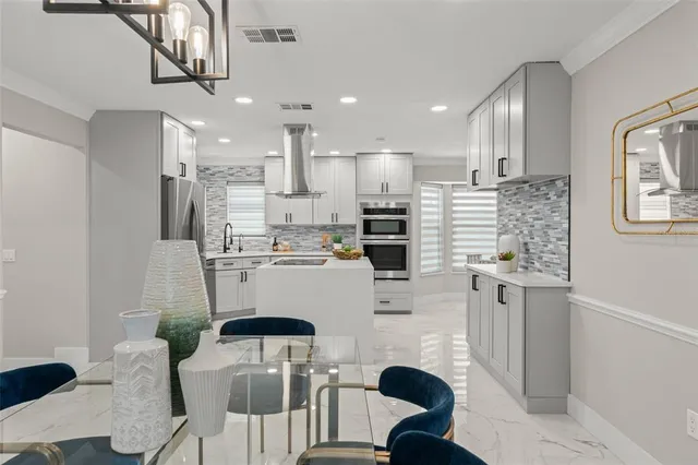 a kitchen with stainless steel appliances a sink a stove and white cabinets