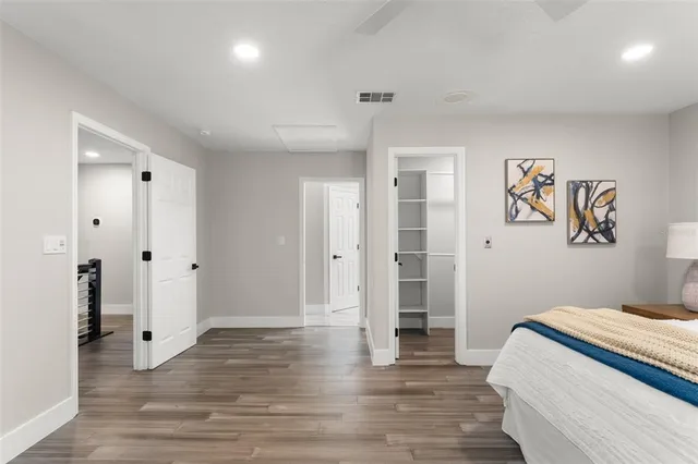a view of an empty room with wooden floor and a ceiling fan
