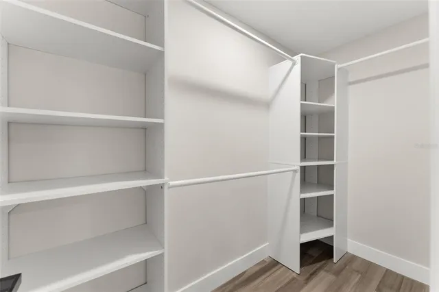 a view of an empty room with wooden floor and a ceiling fan