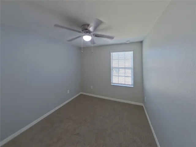 an empty room with a window and a fan