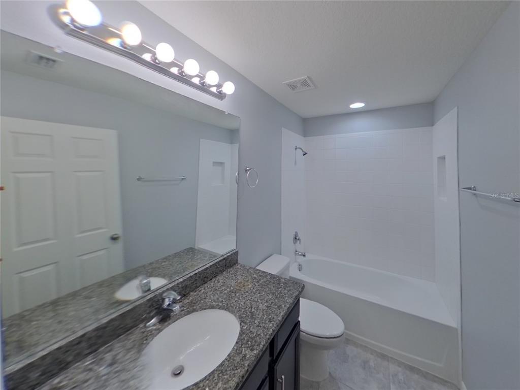 Undisclosed Address Riverview, FL 33578 - Photo 14 of 15 a bathroom with a granite countertop sink a toilet a mirror and shower