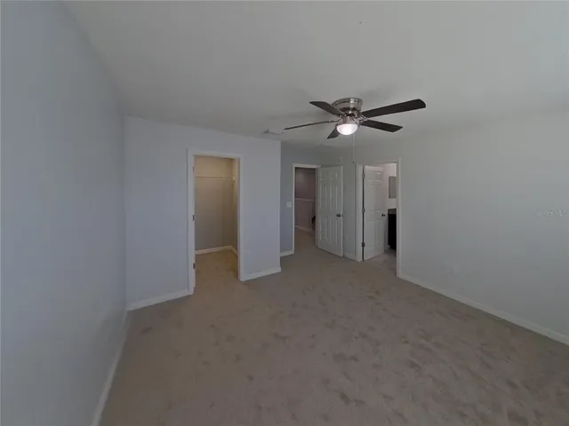 a view of an empty room with a ceiling fan and window