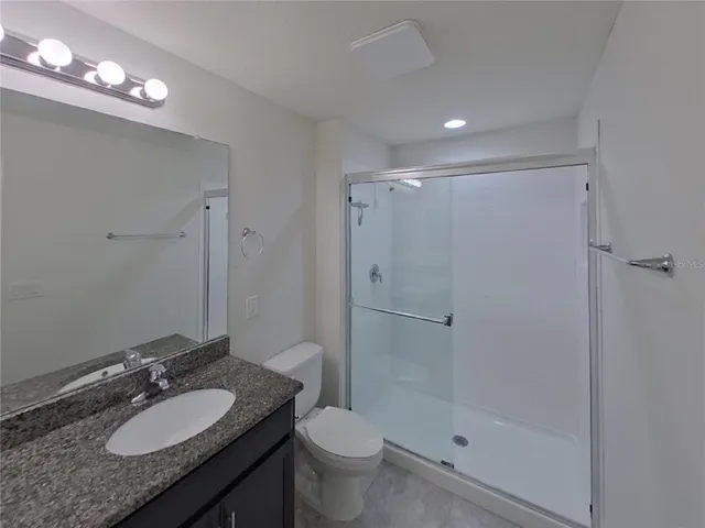 a bathroom with a granite countertop sink toilet a mirror and shower