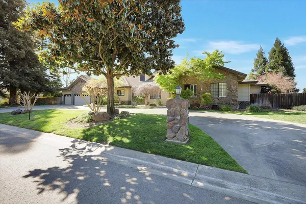 a front view of a house with a yard and tree