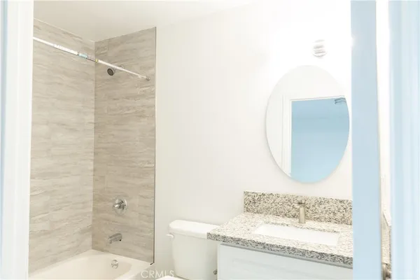 a bathroom with a granite countertop sink a toilet and shower