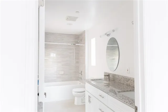 a bathroom with a granite countertop sink a toilet and shower