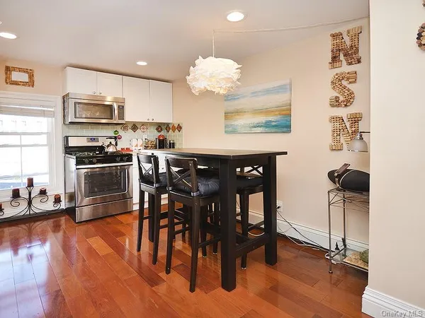 a kitchen with stainless steel appliances granite countertop a stove top oven a sink a dining table and chairs with wooden floor
