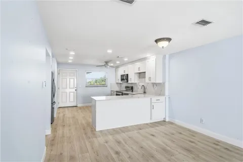 an empty room with wooden floor fan and windows